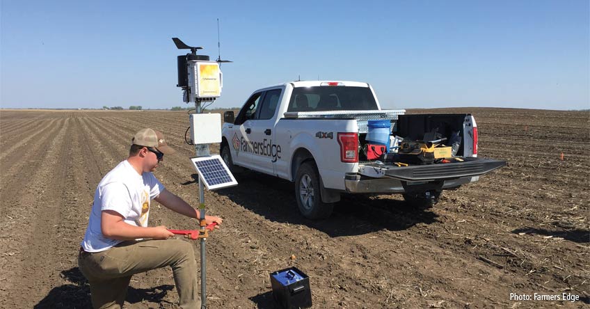 A technician installing an on-farm weather sration