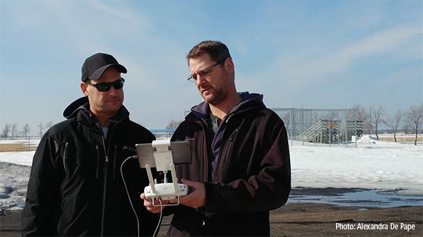 Two men looking at the screen of a tablet attached to a drone controller.